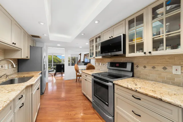 a kitchen with stainless steel appliances granite countertop a refrigerator a stove a sink a dining table and chairs with wooden floor