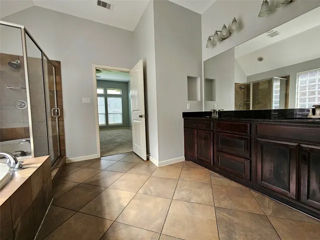 a spacious bathroom with a granite countertop sink a mirror and a bathtub