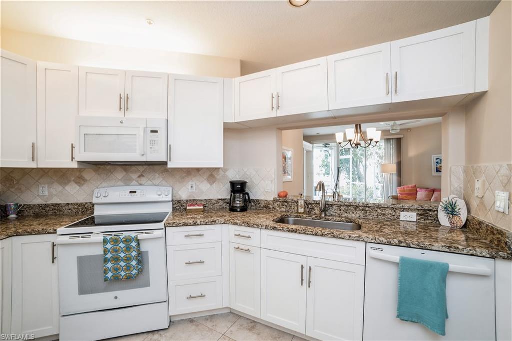 a kitchen with granite countertop white cabinets white appliances and a sink