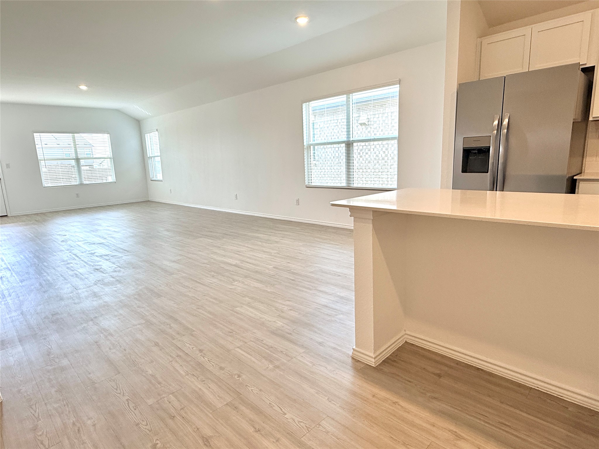 289 Sormonne Loop Kyle, TX 78640 - Photo 16 of 32 Unfurnished living room with vaulted ceiling, recessed lighting, and light wood-type flooring