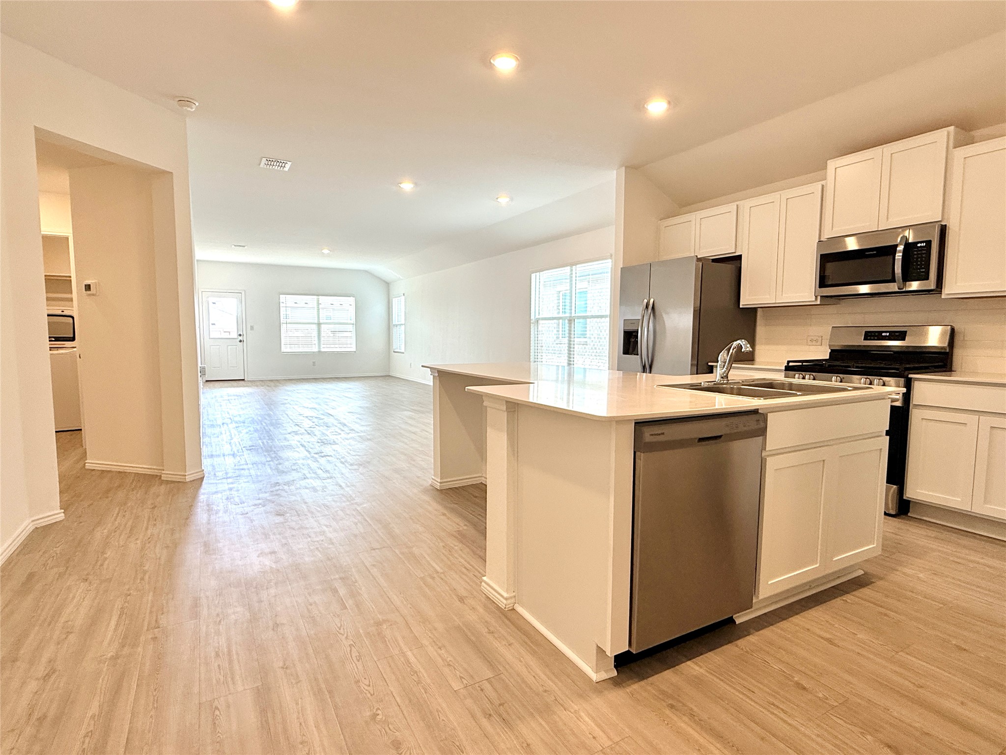 289 Sormonne Loop Kyle, TX 78640 - Photo 32 of 32 Kitchen with white cabinetry, stainless steel appliances, open floor plan, a center island with sink, and light wood-style floors
