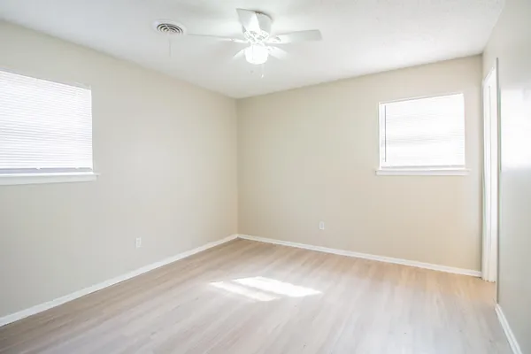 an empty room with a window and a fan