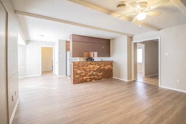 a view of an empty room with wooden floor and a ceiling fan