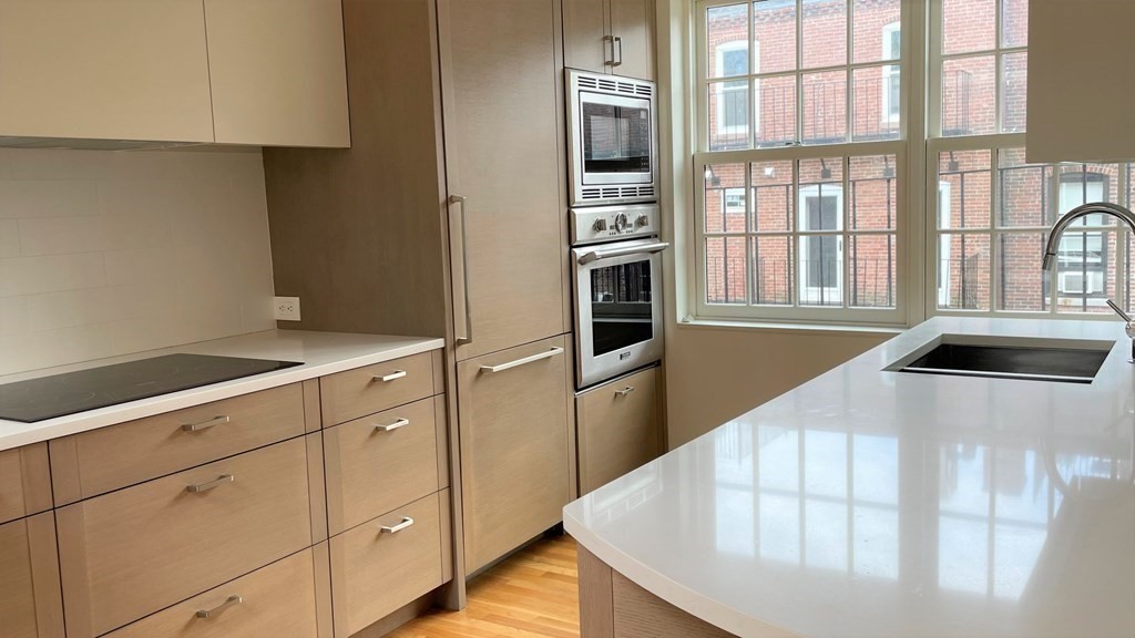 33 Lawrence Street, Unit 2 Boston, MA 02116 - Photo 15 of 38 a kitchen with stainless steel appliances kitchen island a refrigerator sink and cabinets
