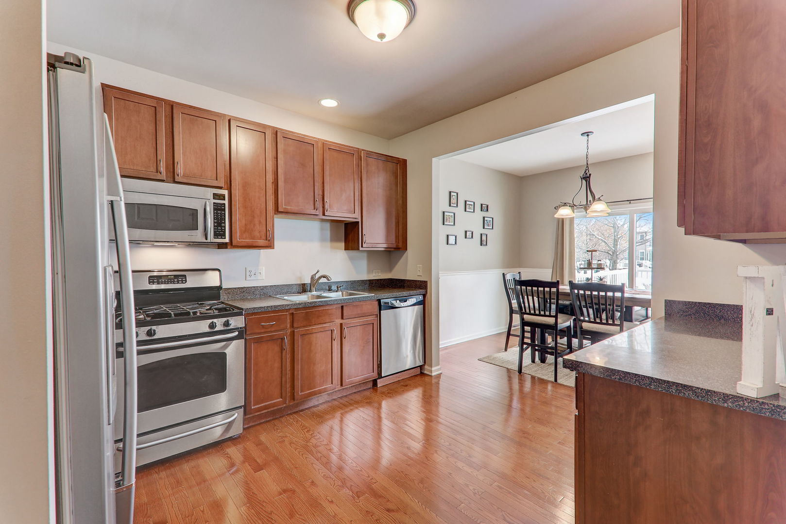 980 Oak Ridge Boulevard Elgin, IL 60120 - Photo 15 of 42 a kitchen with stainless steel appliances granite countertop a stove top oven a sink dishwasher a dining table and chairs with wooden floor