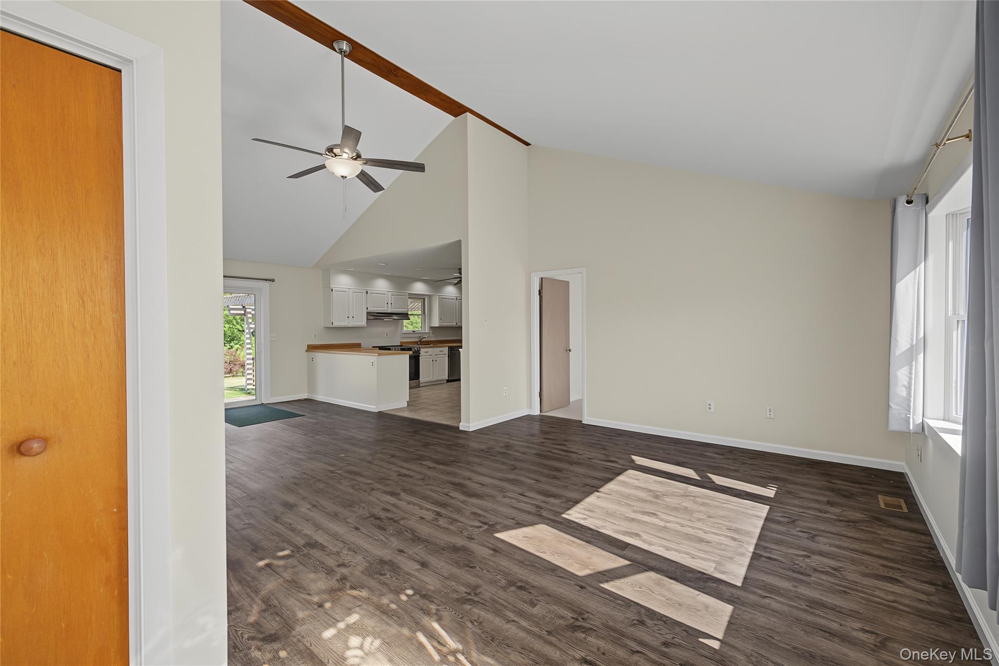 318 Cornwall Hill Road Patterson, NY 12563 - Photo 11 of 38 Spacious living area featuring vaulted ceilings with exposed wood beams, a ceiling fan with integrated lighting, and dark wood-finish flooring