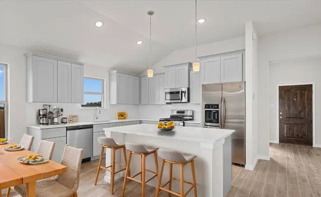 a kitchen with stainless steel appliances a refrigerator a sink a stove a dining table and chairs