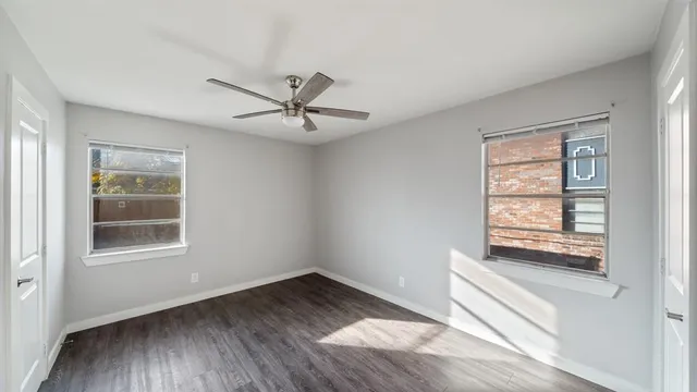 a view of an empty room with a window and wooden floor