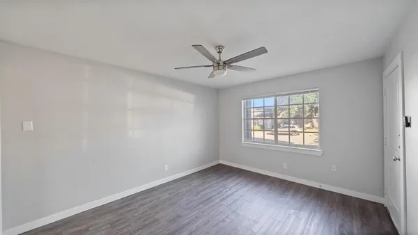 an empty room with wooden floor and windows