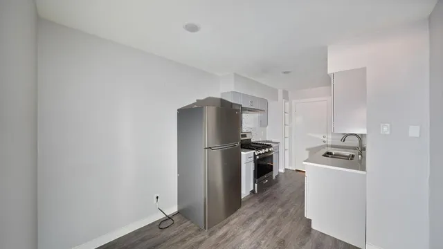 a kitchen with a refrigerator stove and wooden floor
