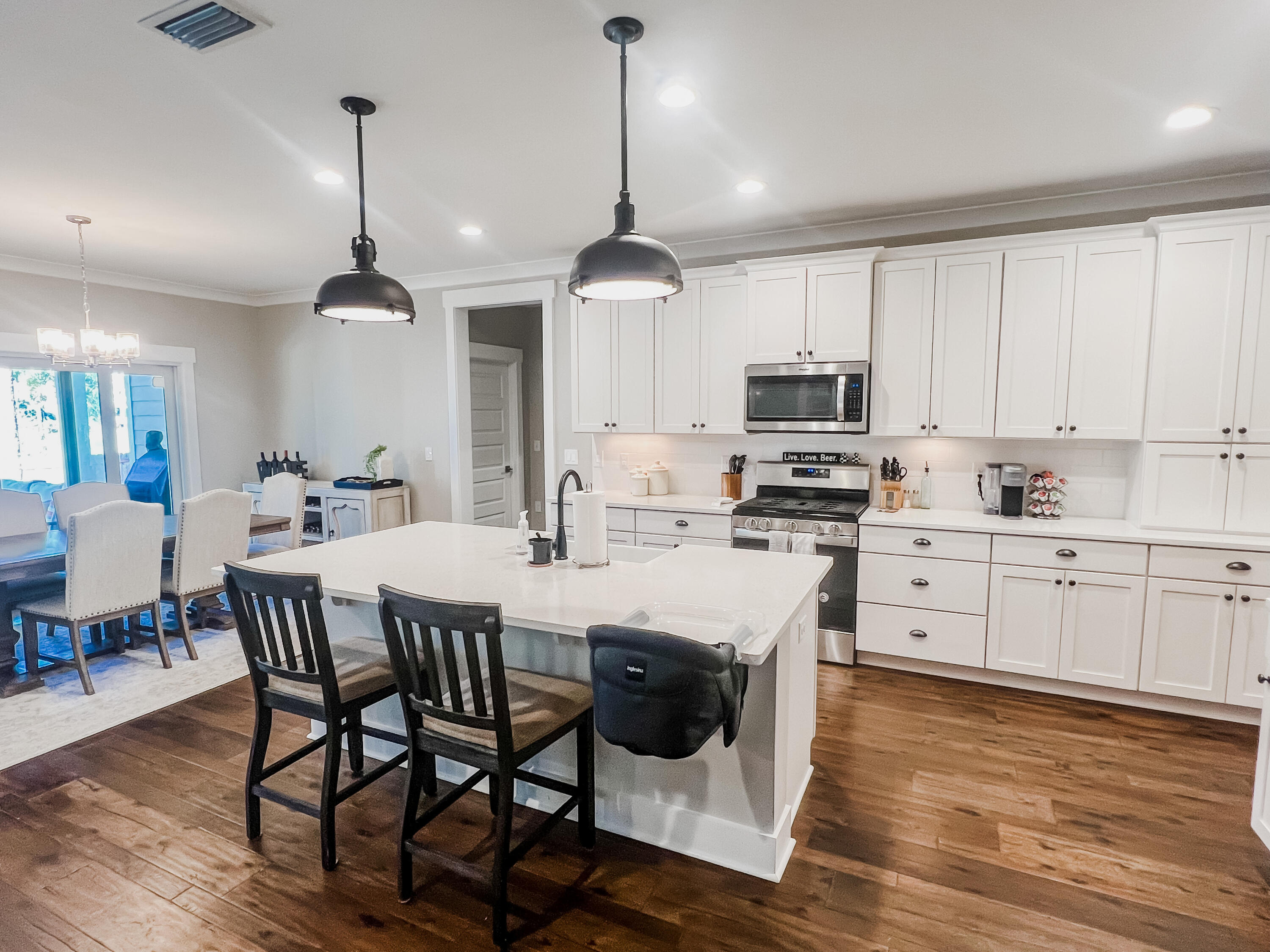 1159 Deer Moss Loop Niceville, FL 32578 - Photo 6 of 24 a kitchen with stainless steel appliances granite countertop a stove a sink a microwave a dining table and chairs with wooden floor