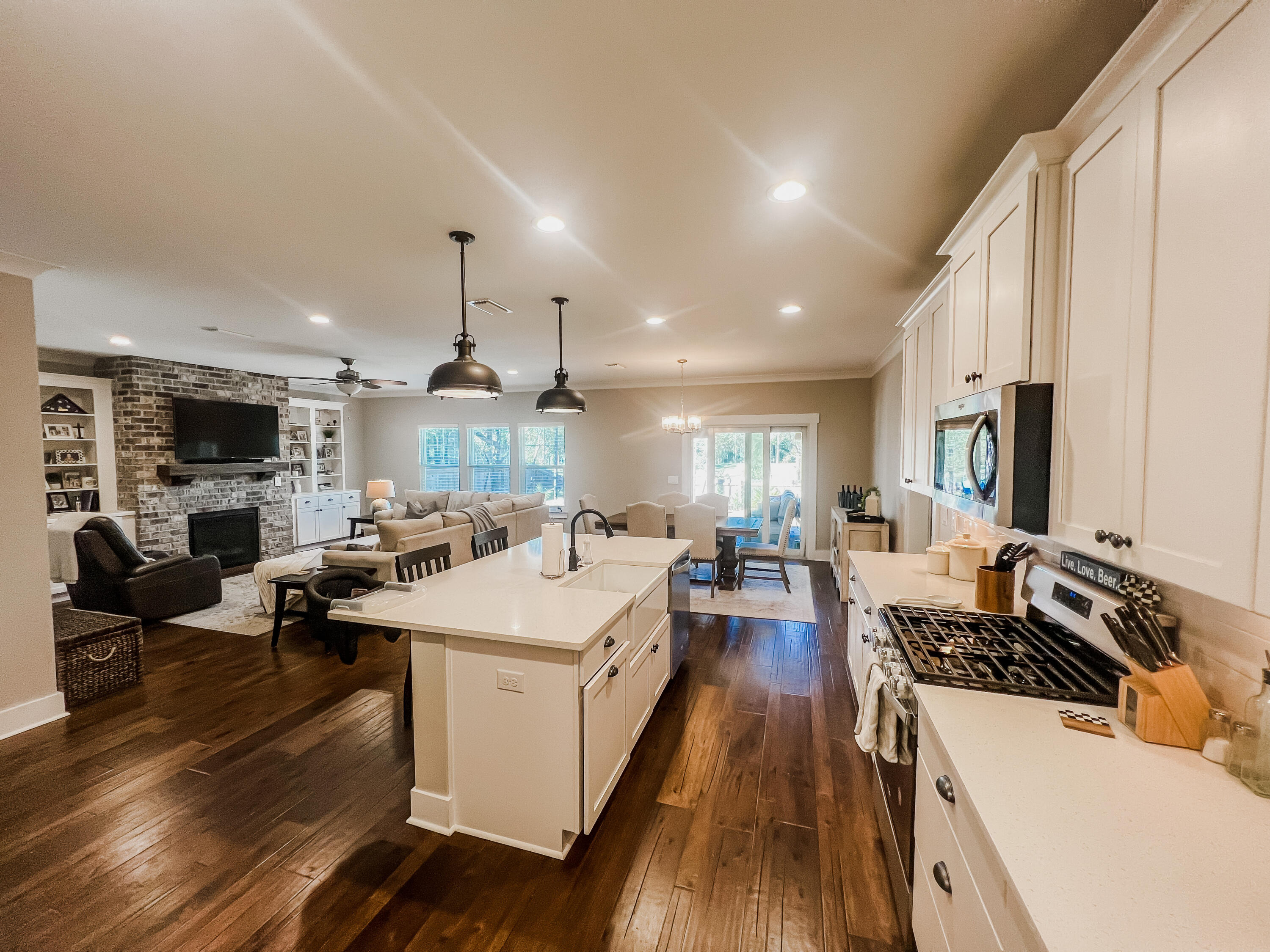 1159 Deer Moss Loop Niceville, FL 32578 - Photo 7 of 24 a large kitchen with stainless steel appliances a stove a sink dishwasher and a dining table with wooden floor