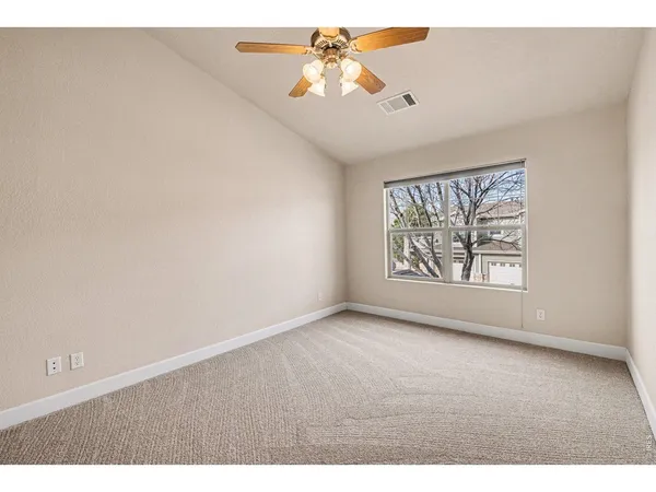 a view of an empty room with window and a chandelier fan