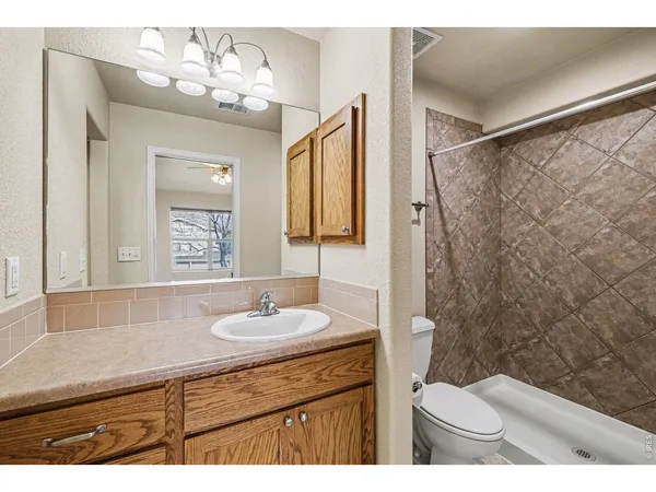 a bathroom with a granite countertop sink toilet and shower
