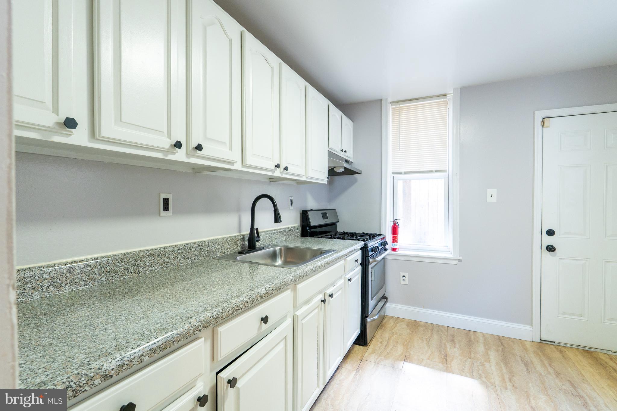 1826 McClellan Street Philadelphia, PA 19145 - Photo 6 of 22 a kitchen with granite countertop a sink stainless steel appliances white cabinets and a window