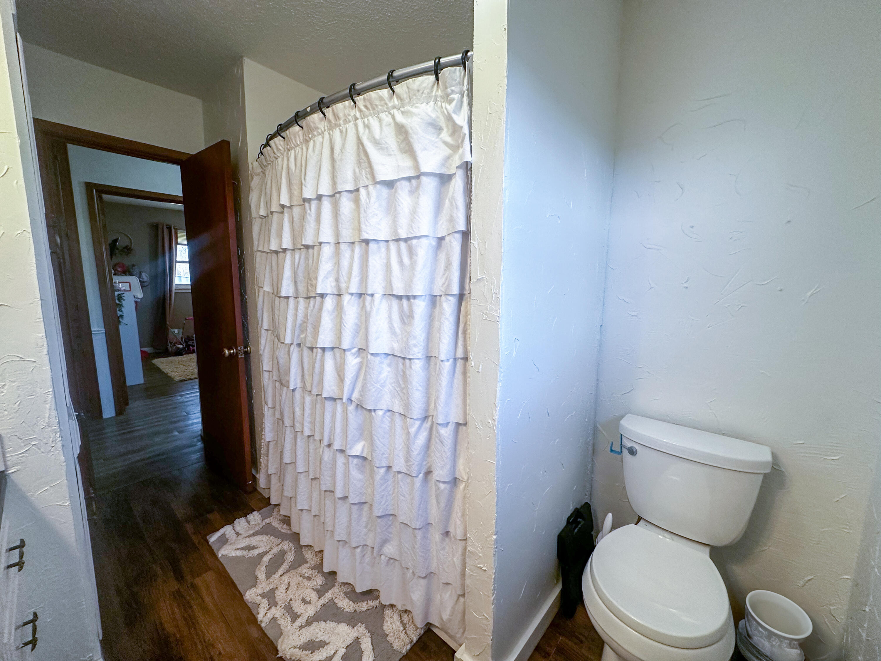 511 Childress Avenue Turkey, TX 79261 - Photo 7 of 20 a white toilet sitting next to a shower curtain