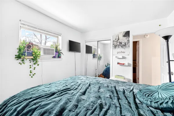 a bedroom with a bed potted plant on the dresser and a large window