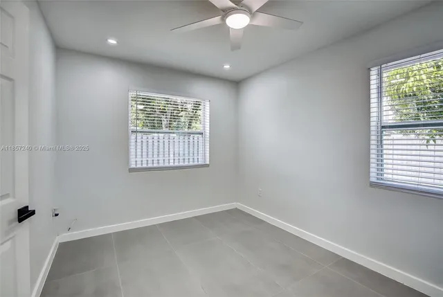 an empty room with windows and fan
