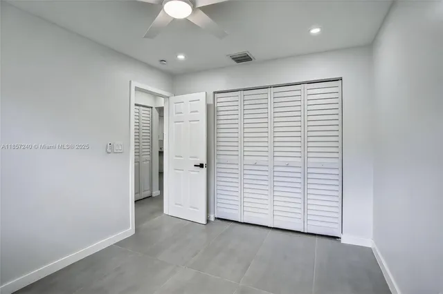 an empty room with closet and a ceiling fan