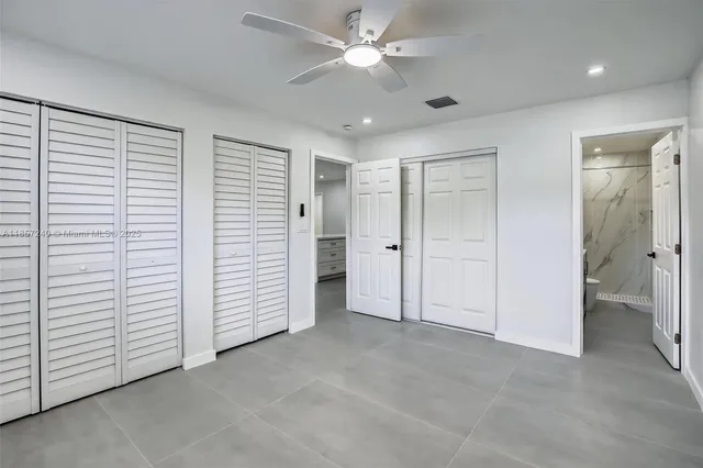 a view of an empty room with closet and a ceiling fan