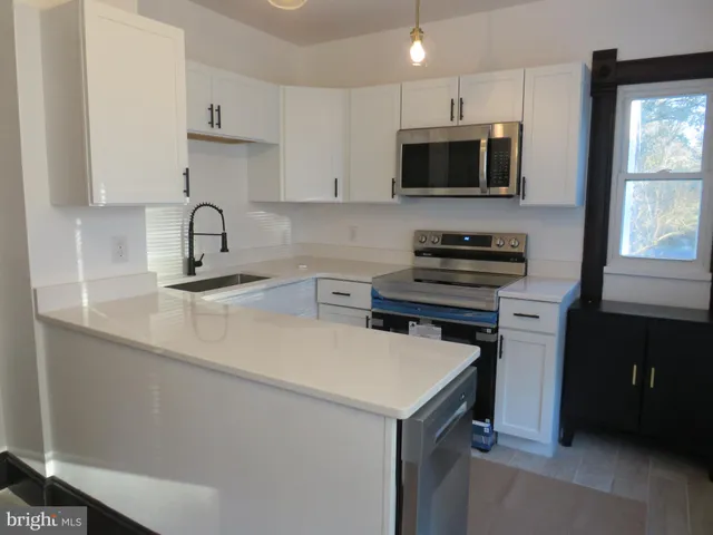 a kitchen with a sink a stove top oven and cabinetry