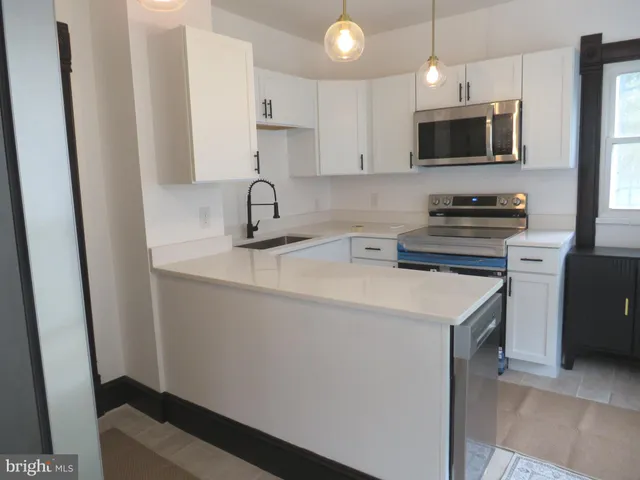 a kitchen with stainless steel appliances a sink a stove a microwave a refrigerator a cabinets and wooden floor