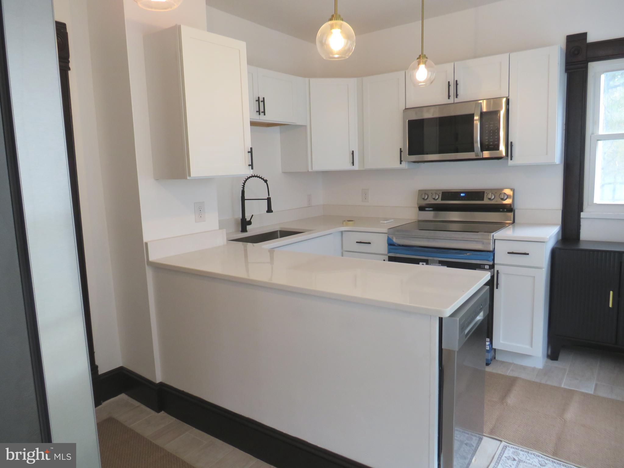 3372 Sackertown Road Crisfield, MD 21817 - Photo 14 of 29 a kitchen with stainless steel appliances a sink a stove a microwave a refrigerator a cabinets and wooden floor