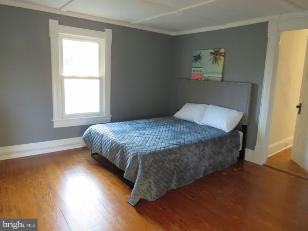 a view of a bedroom with wooden floor and windows