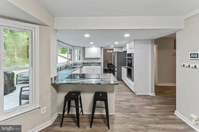 a kitchen with kitchen island a dining table chairs stainless steel appliances and window