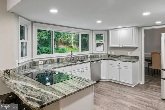 a kitchen with granite countertop a sink and white cabinets