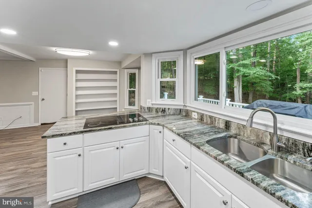 a kitchen with granite countertop a sink and white cabinets with wooden floor