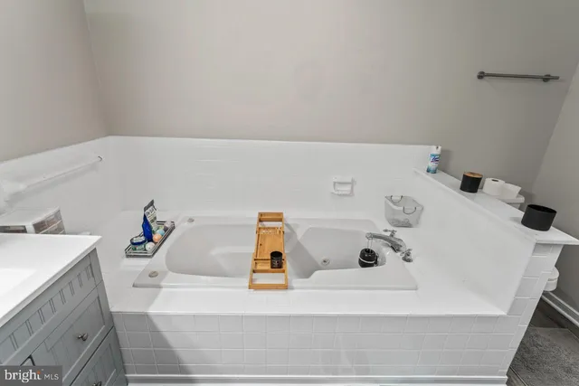 a bathroom with a tub sink and white cabinets