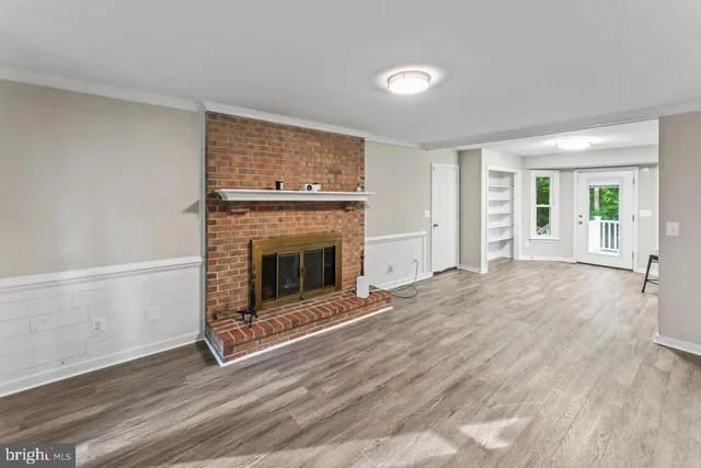 a view of empty room with wooden floor and fireplace