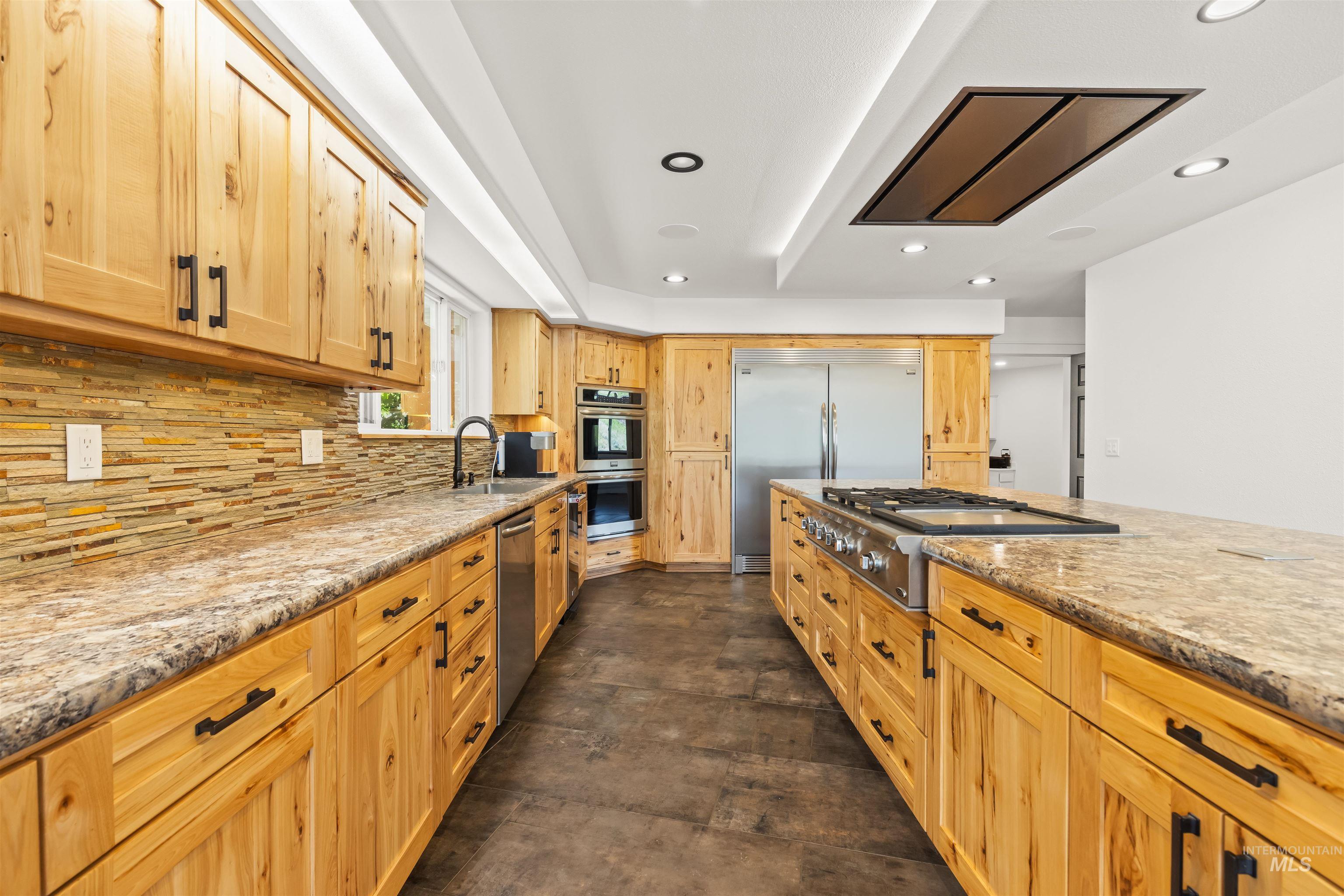 3360 East Main Street Lewiston, ID 83501 - Photo 14 of 50 Spacious kitchen featuring a large central island with a gas range, abundant wood cabinetry, integrated stainless steel appliances, and stone-look countertops
