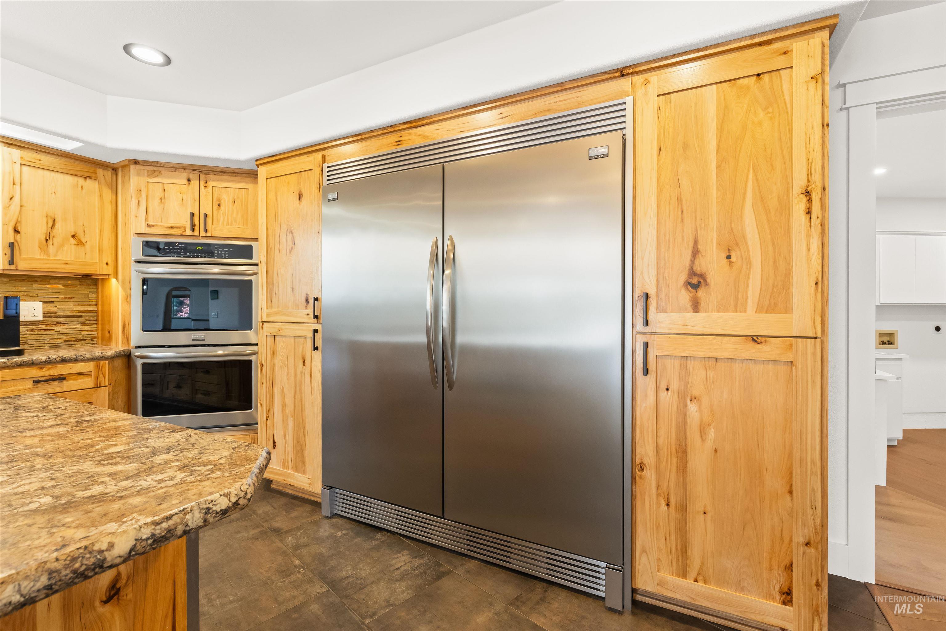 3360 East Main Street Lewiston, ID 83501 - Photo 15 of 50 Gourmet kitchen featuring a built-in stainless steel refrigerator, double wall ovens, wood cabinetry, and speckled stone countertops