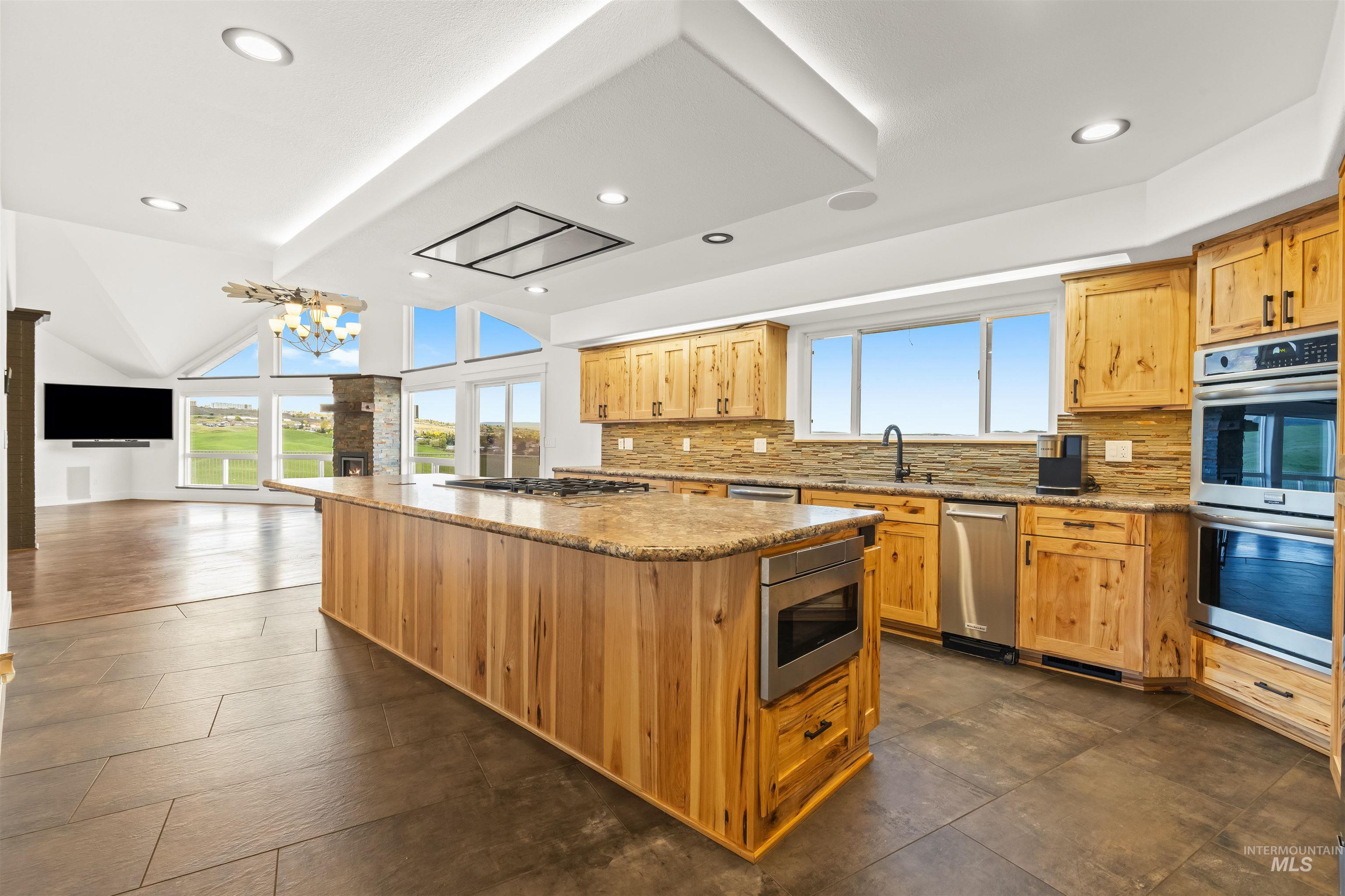 3360 East Main Street Lewiston, ID 83501 - Photo 17 of 50 Kitchen featuring a large central island with integrated microwave, wood cabinetry, stone countertops, and stainless steel appliances