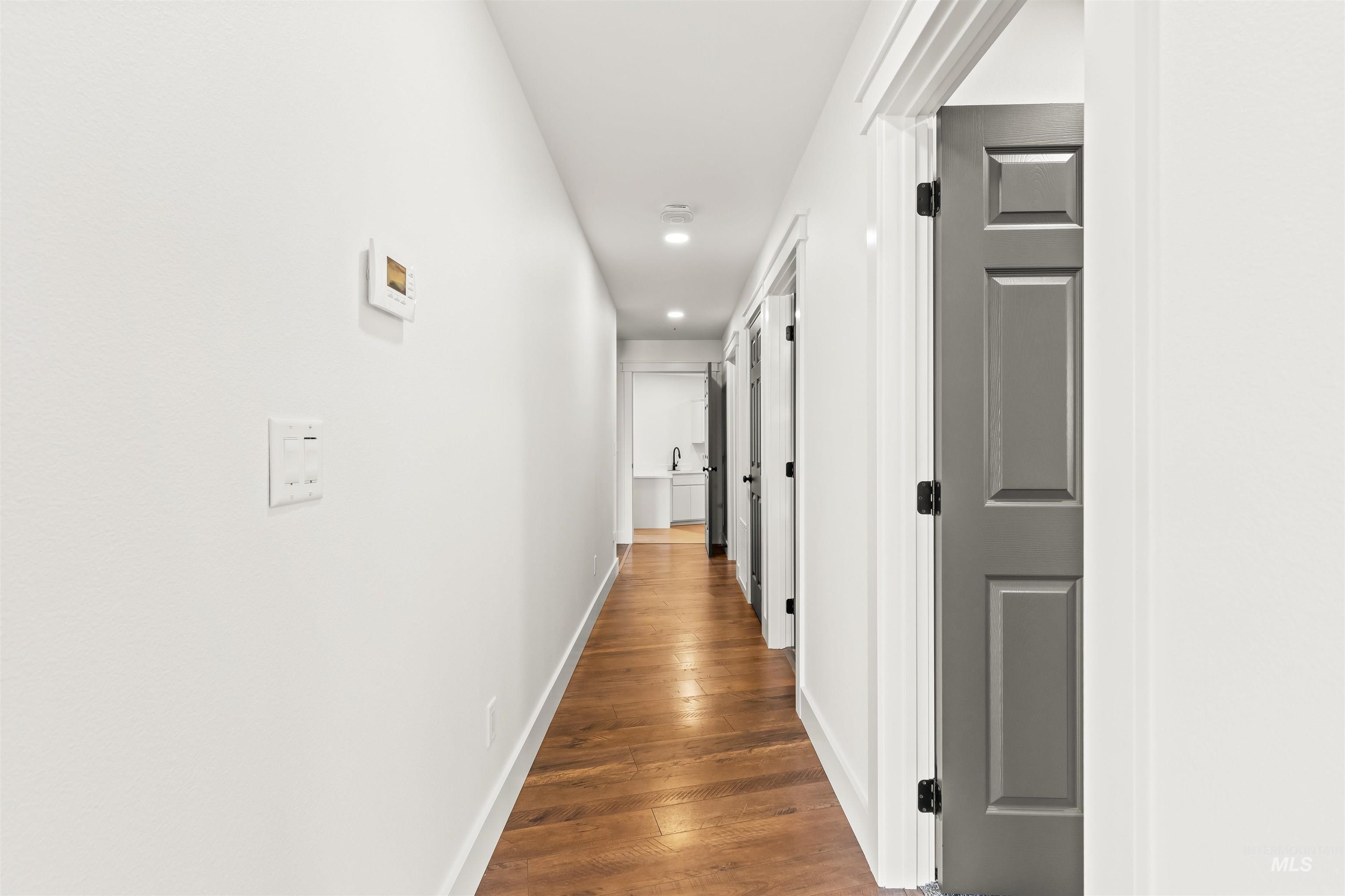 3360 East Main Street Lewiston, ID 83501 - Photo 18 of 50 Hallway featuring wood-finish flooring, white walls, recessed lighting, and contrasting grey paneled doors with black hardware