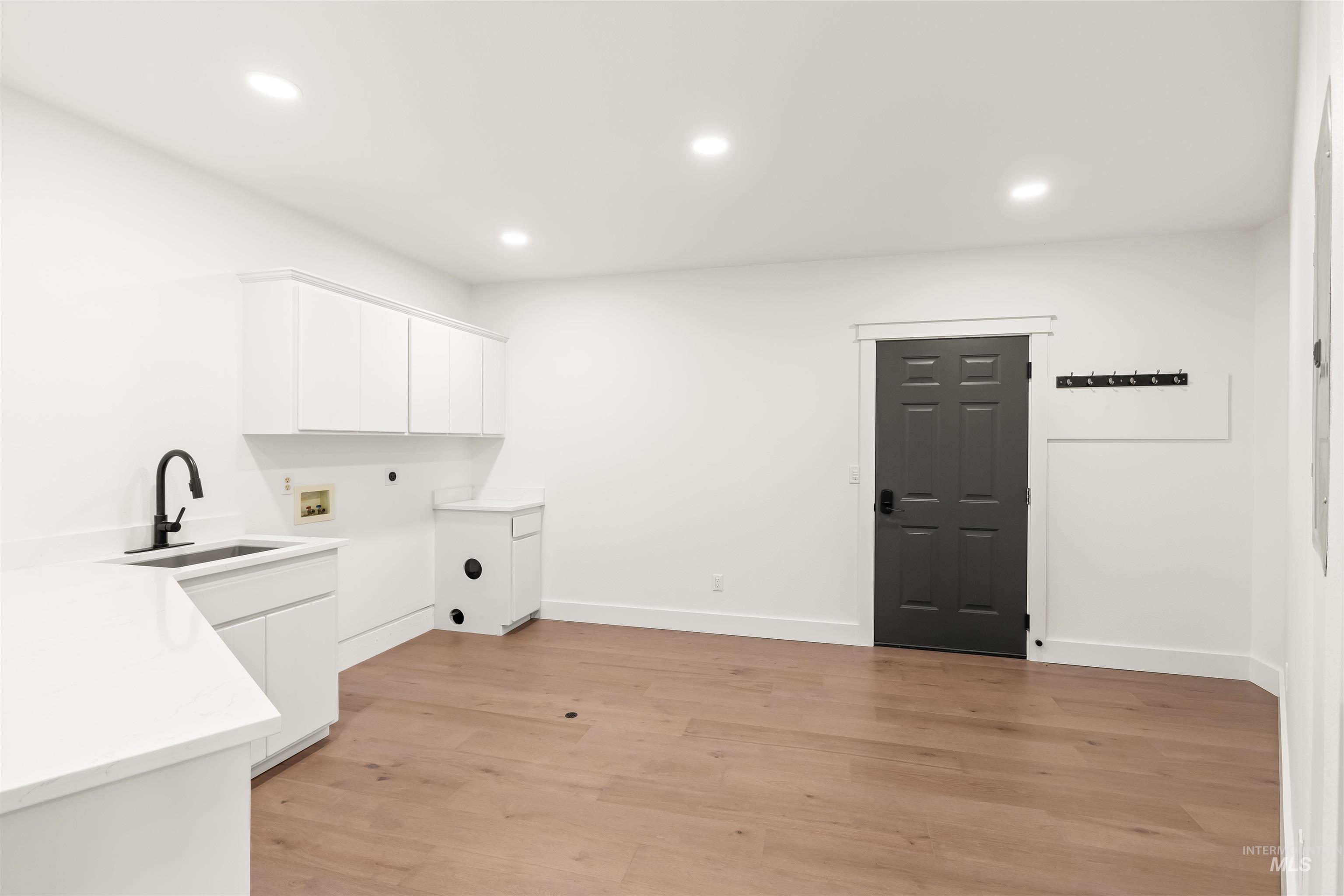 3360 East Main Street Lewiston, ID 83501 - Photo 23 of 50 Spacious utility room featuring a built-in sink with a matte black faucet, white cabinetry, integrated countertop, wood-finish flooring, and recessed lighting