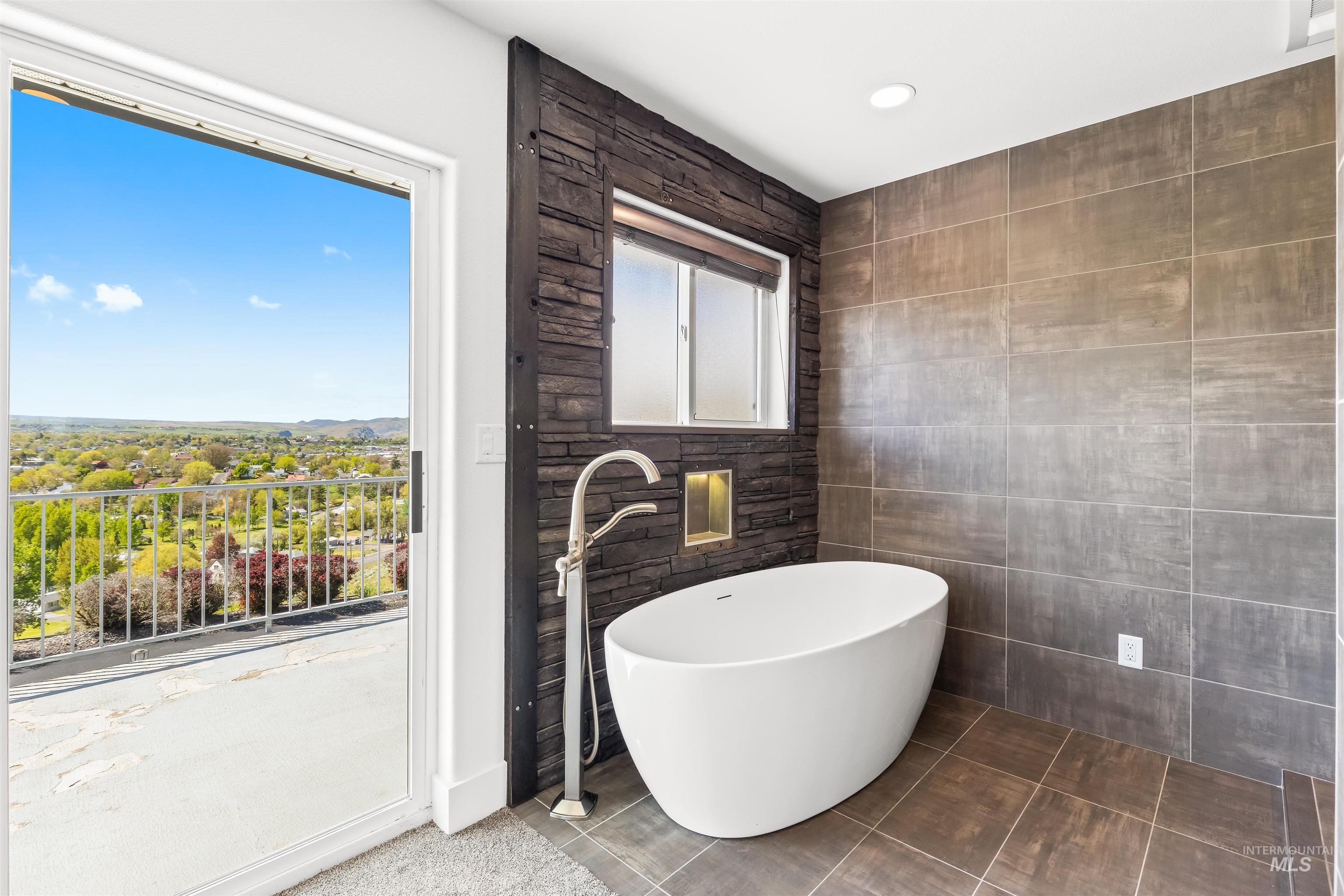 3360 East Main Street Lewiston, ID 83501 - Photo 28 of 50 Freestanding soaking tub with a floor-mounted faucet, set against a dark stone-clad accent wall