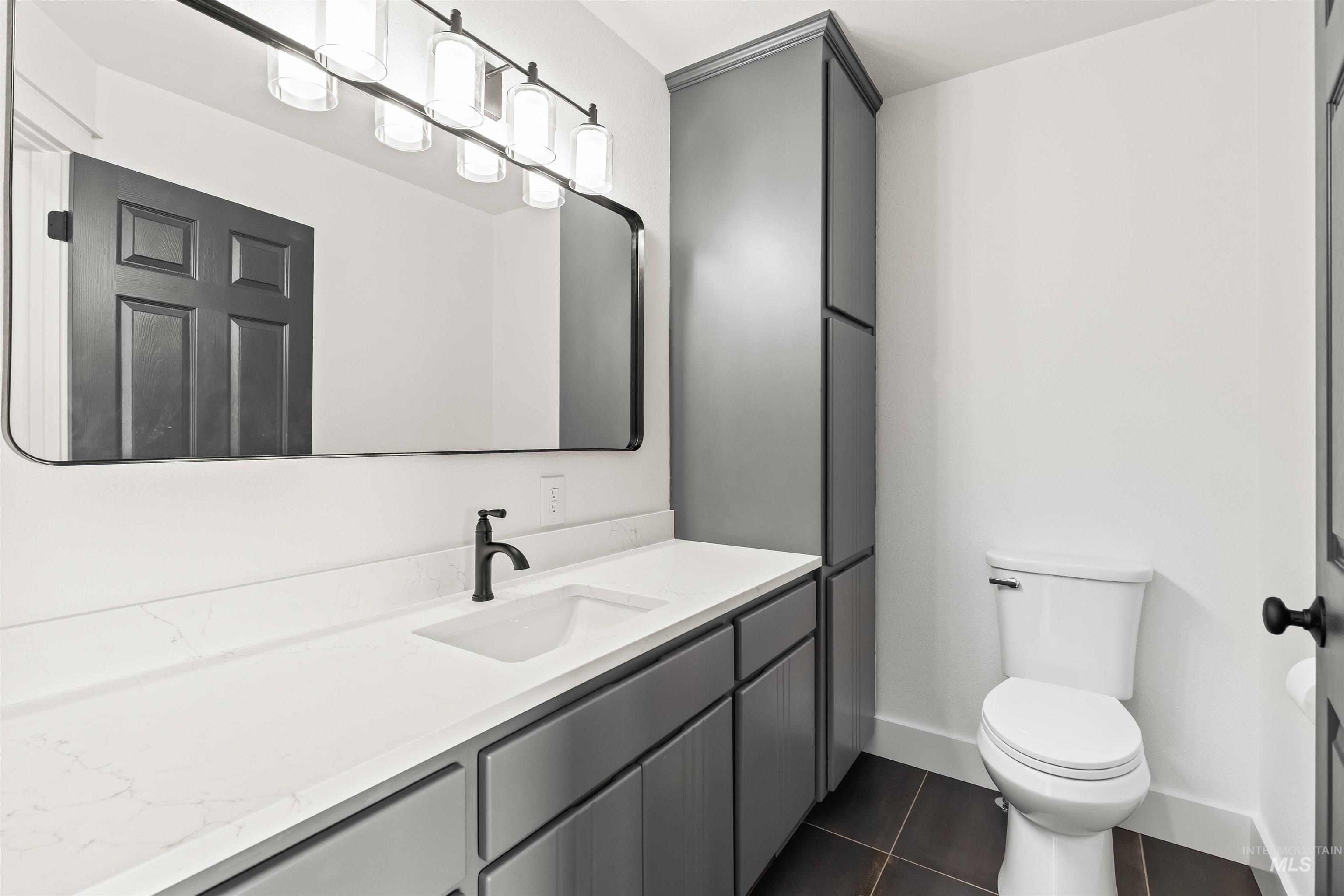 3360 East Main Street Lewiston, ID 83501 - Photo 31 of 50 Bathroom featuring a white countertop with integrated sink, matte black faucet, gray cabinetry, large framed mirror, and built-in storage tower