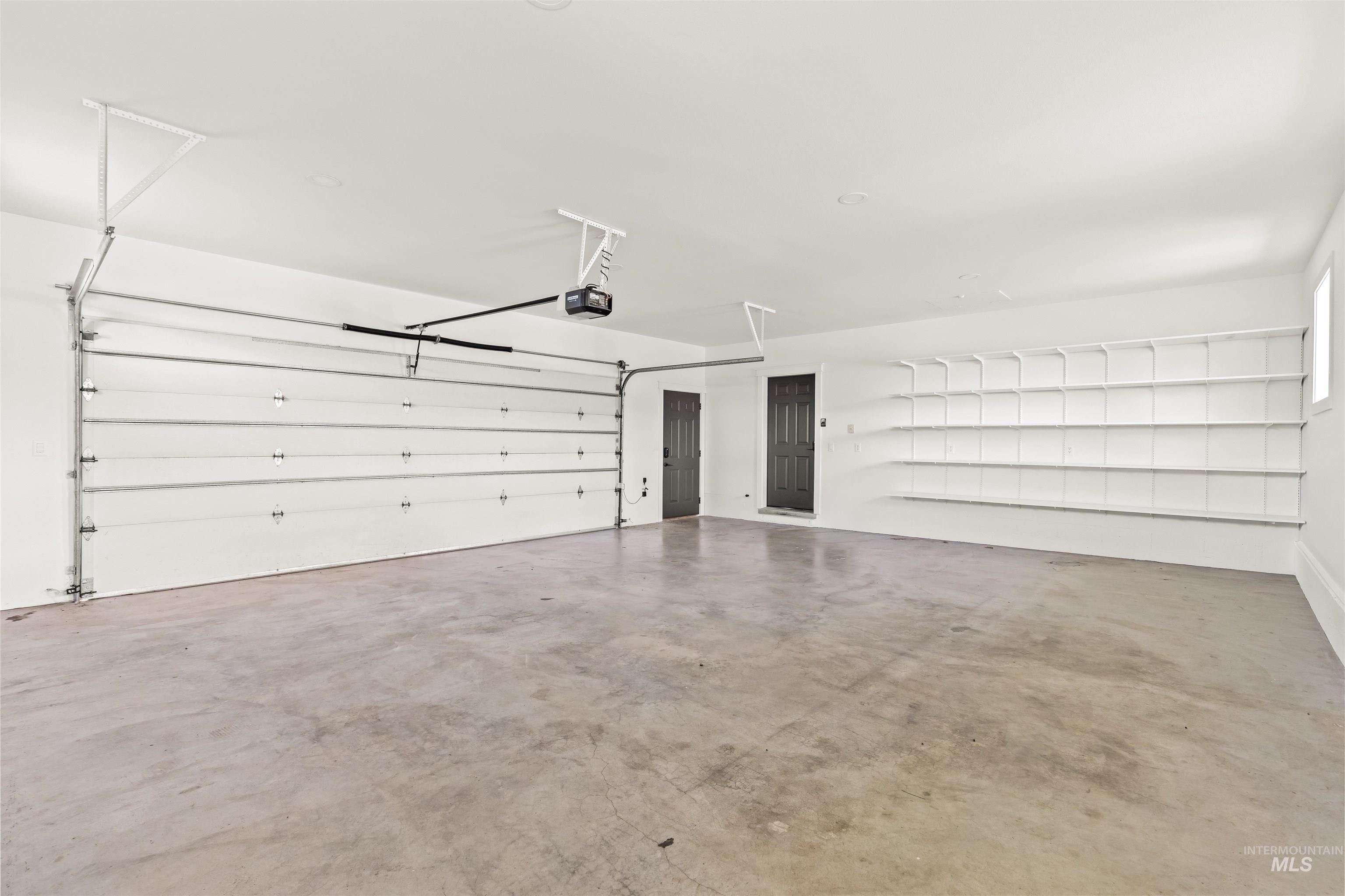 3360 East Main Street Lewiston, ID 83501 - Photo 34 of 50 Spacious garage featuring a concrete floor, an overhead garage door opener, dark-paneled doors, and extensive built-in shelving