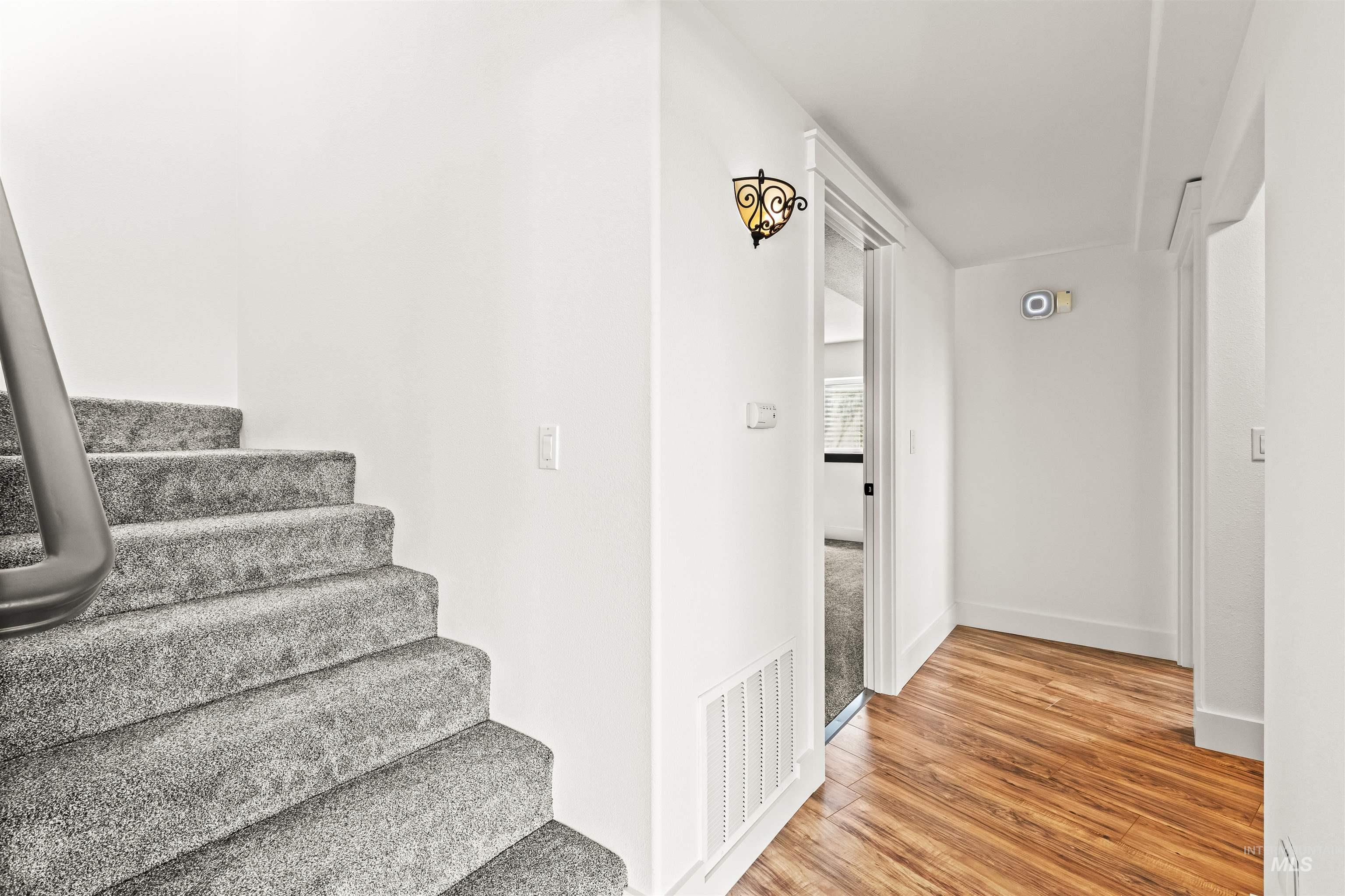 3360 East Main Street Lewiston, ID 83501 - Photo 39 of 50 Carpeted staircase with a metal handrail, white walls, and wood-finish flooring
