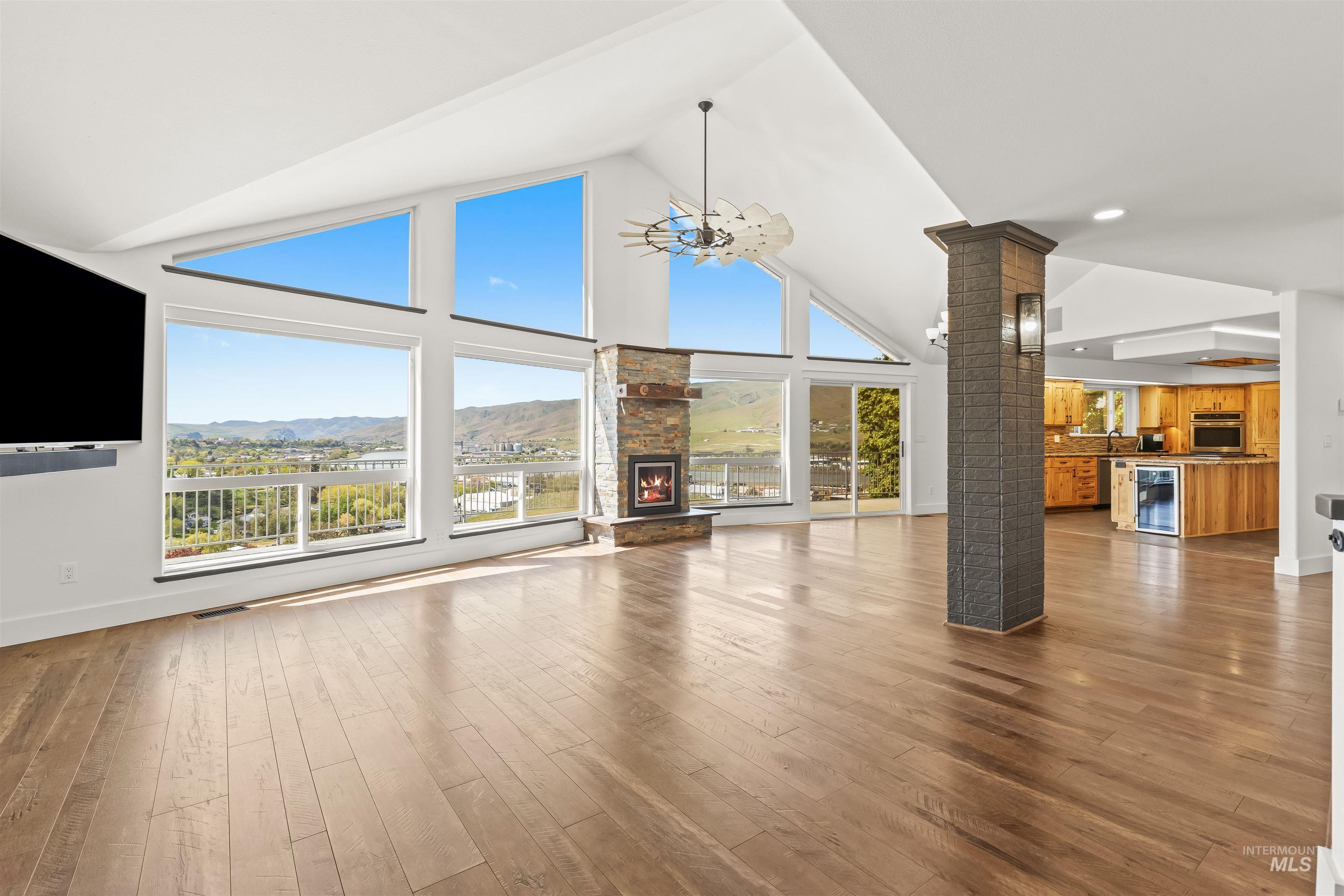 3360 East Main Street Lewiston, ID 83501 - Photo 42 of 50 Open-concept living area featuring vaulted ceilings, a stone fireplace, wood-finish flooring, and expansive windows