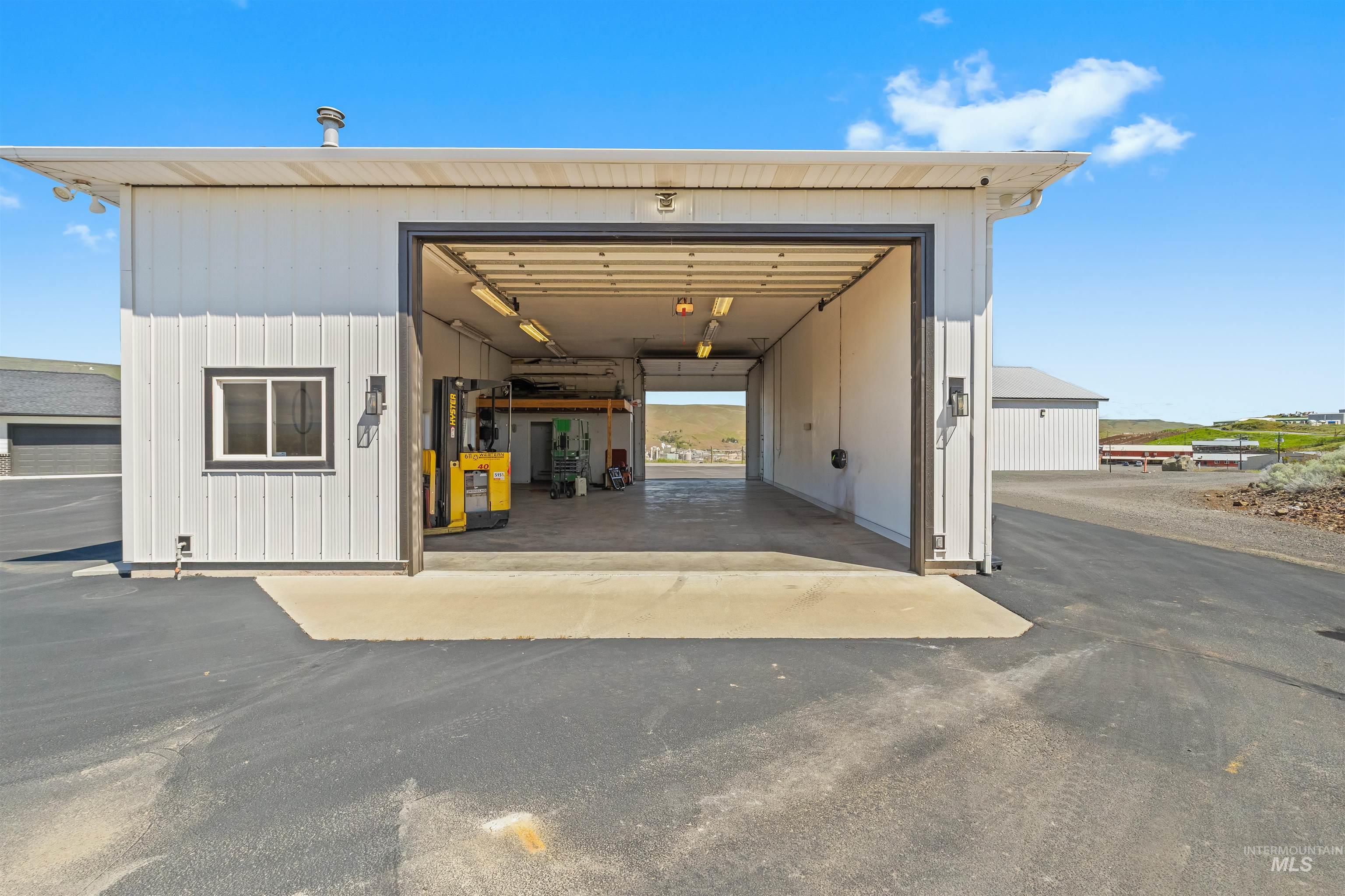 3360 East Main Street Lewiston, ID 83501 - Photo 46 of 50 Spacious white metal-sided building featuring a large open bay, concrete flooring, and multiple overhead light fixtures