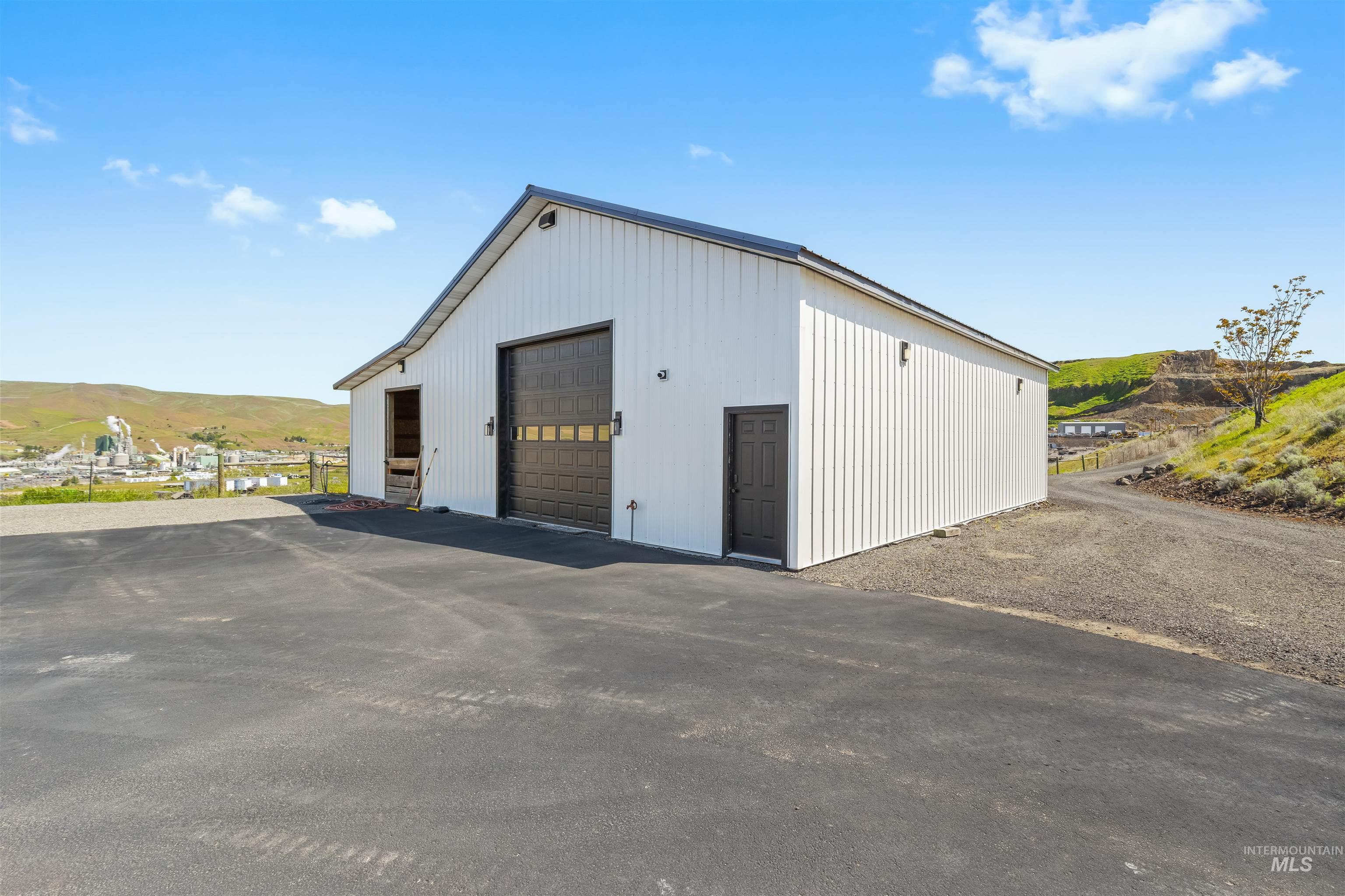 3360 East Main Street Lewiston, ID 83501 - Photo 47 of 50 White-paneled outbuilding featuring a dark sectional garage door, a dark entry door, and a dark asphalt driveway