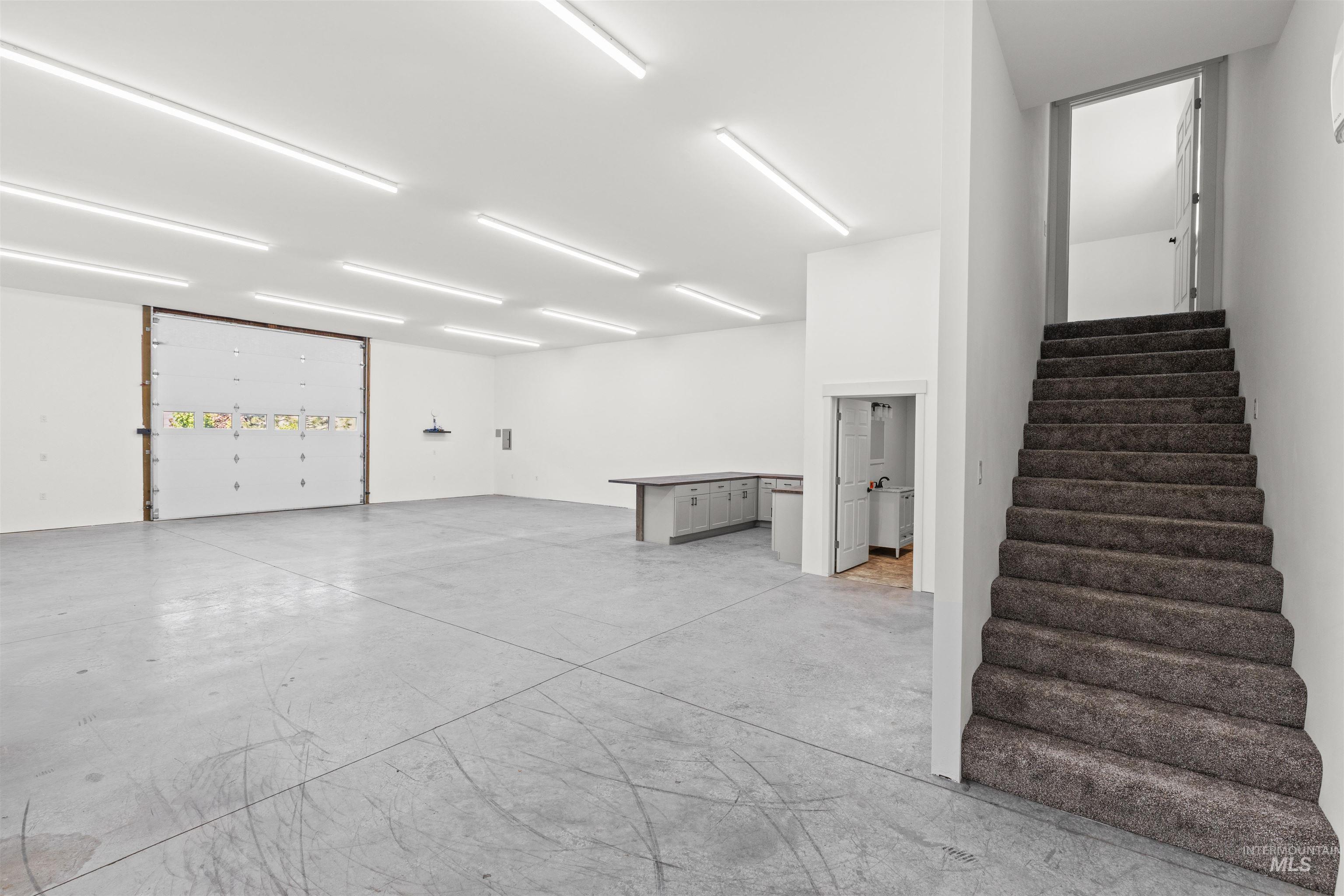 3360 East Main Street Lewiston, ID 83501 - Photo 48 of 50 Expansive open-concept space featuring a large roll-up door, polished concrete flooring, numerous ceiling-mounted light fixtures, and a built-in counter with cabinetry