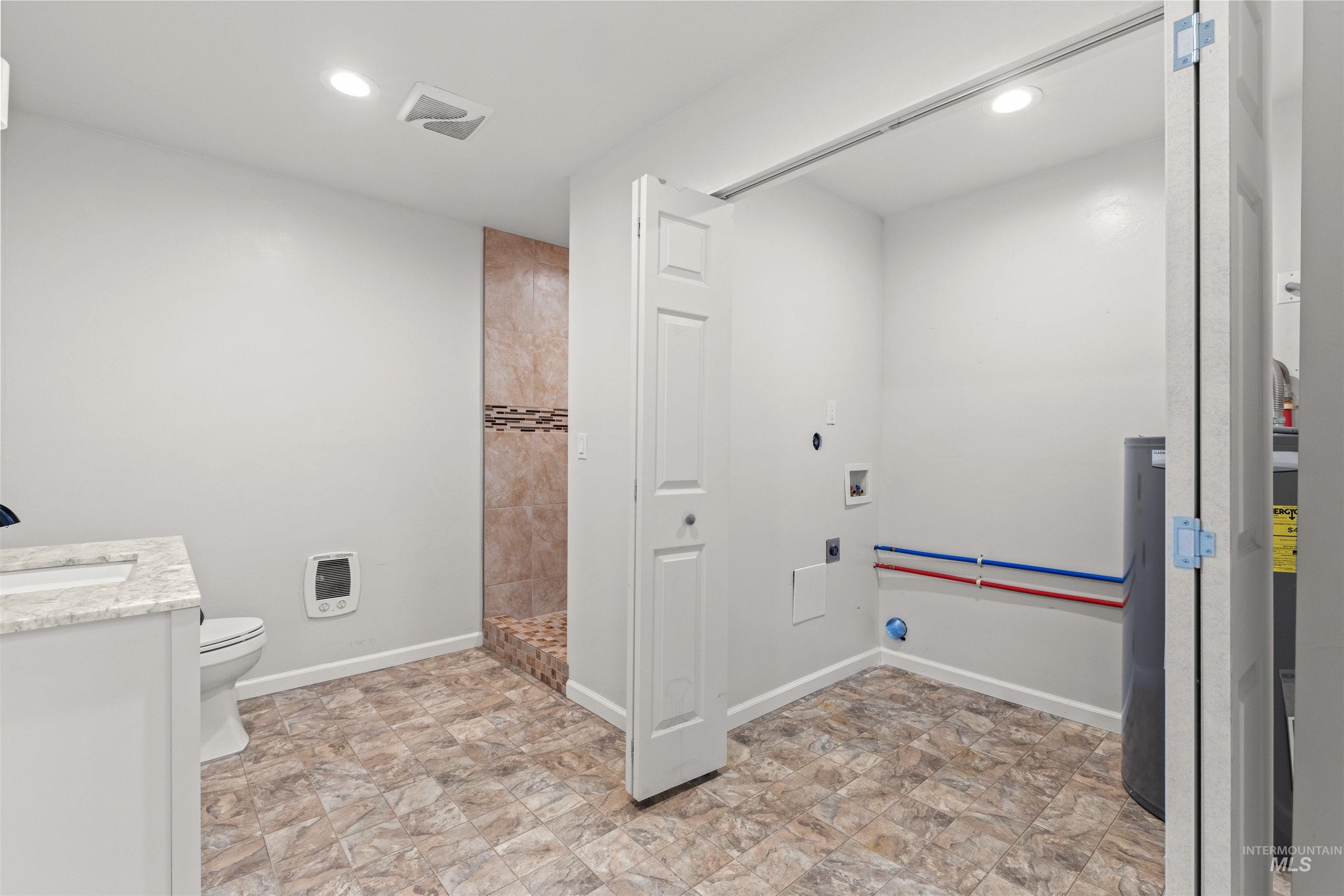 3360 East Main Street Lewiston, ID 83501 - Photo 49 of 50 Bathroom featuring a tiled walk-in shower with decorative mosaic accent, a vanity with a light-colored countertop and integrated sink, and a toilet