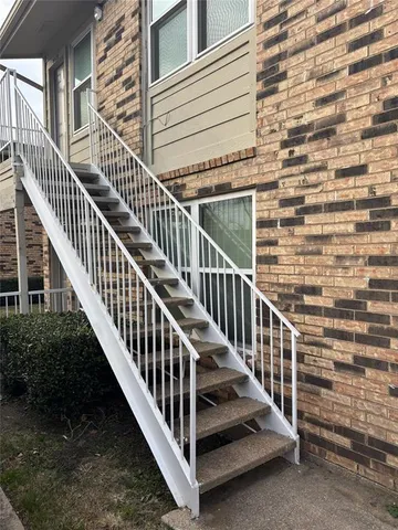 a view of staircase with railing and a view of a house
