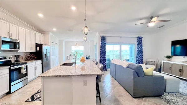 a living room with furniture a flat screen tv and kitchen view