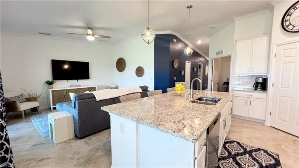 a living room with granite countertop couches a coffee table and flat screen tv with kitchen view